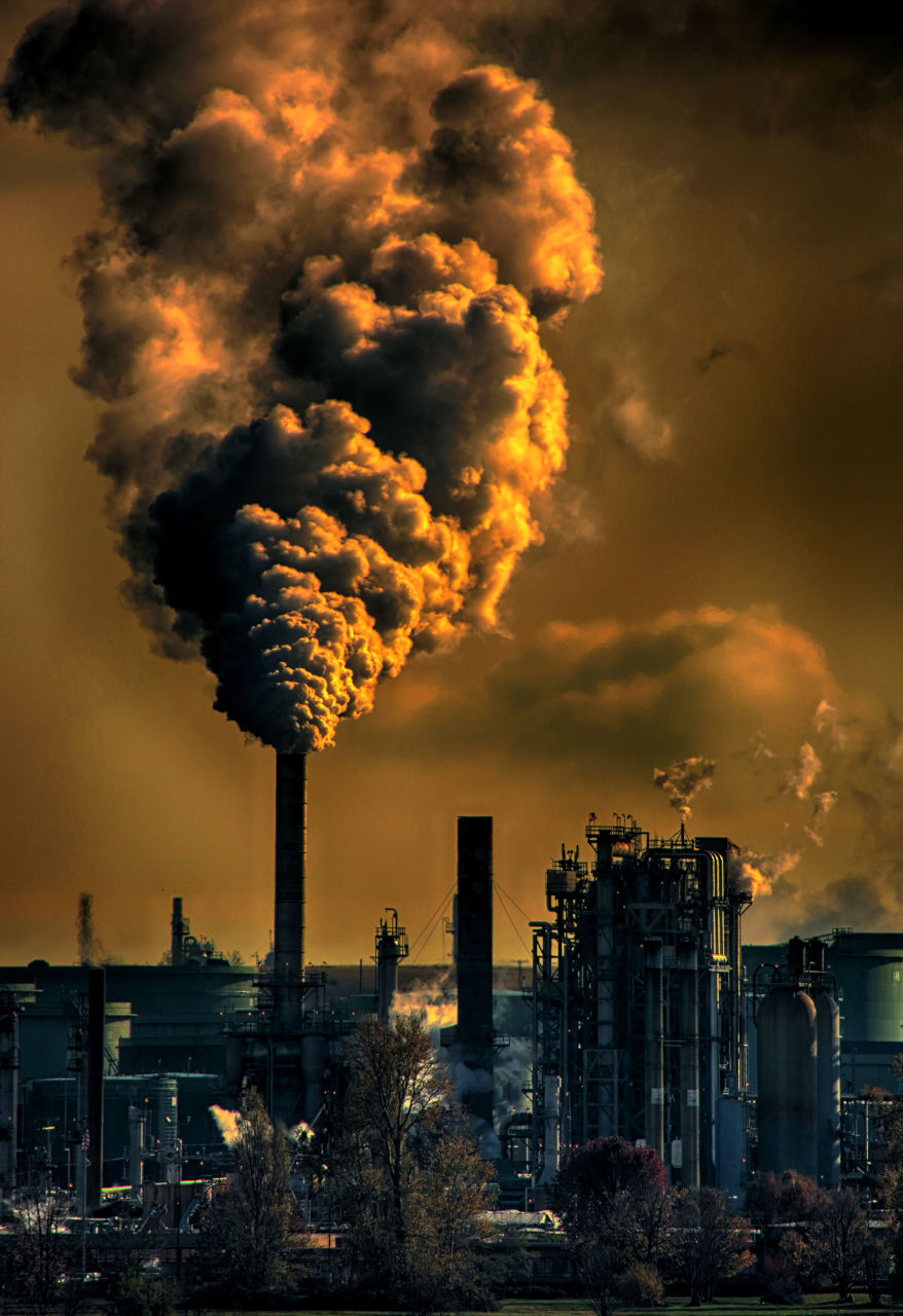 Photo d'une zone industrielle dont on voit des fumées épaisses s'échapper.